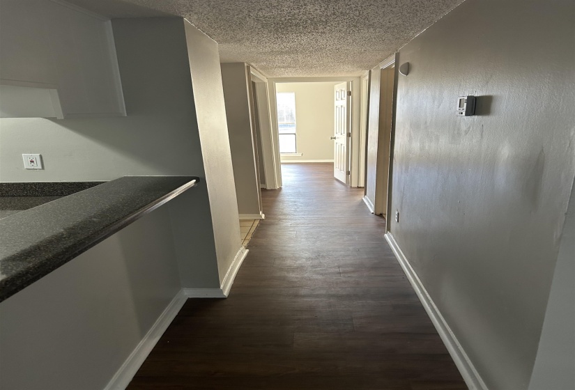 Hallway featuring dark wood-style floors and a textured ceiling