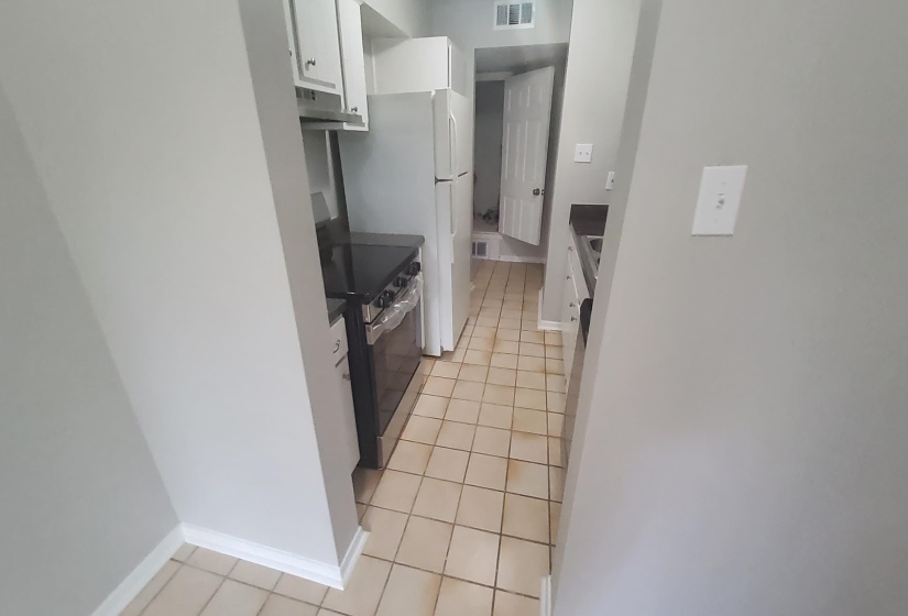 Kitchen with white cabinetry, stainless steel electric range, light tile patterned flooring, and under cabinet range hood