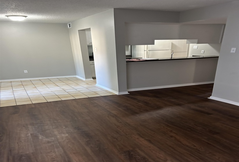 Kitchen with a textured ceiling, wood finished floors, and freestanding refrigerator