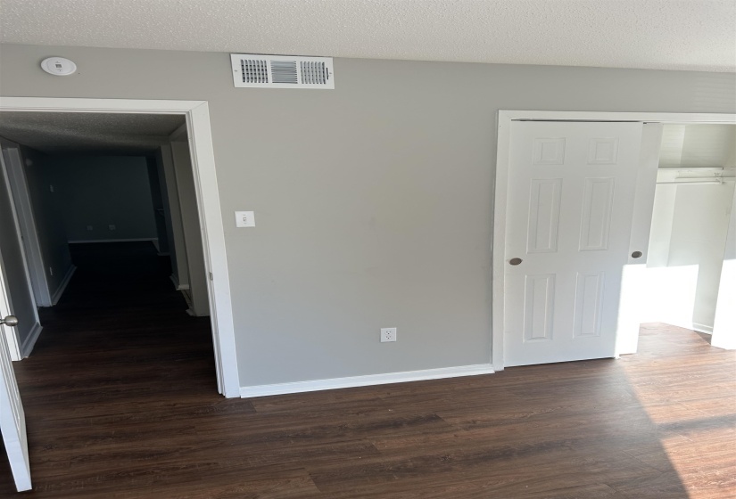Unfurnished bedroom featuring a textured ceiling, dark wood-type flooring, and a closet