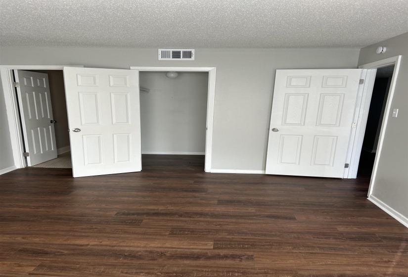 Unfurnished bedroom featuring a closet, a textured ceiling, and dark wood-type flooring