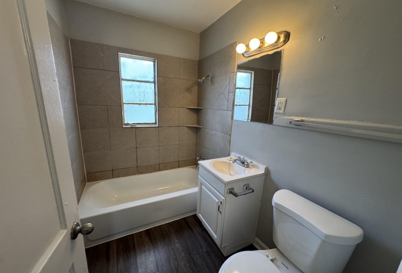 Bathroom featuring vanity, tub / shower combination, and dark wood-style flooring