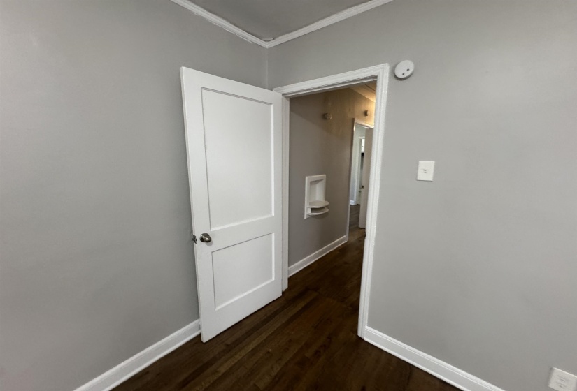 Corridor with ornamental molding and dark wood-style flooring