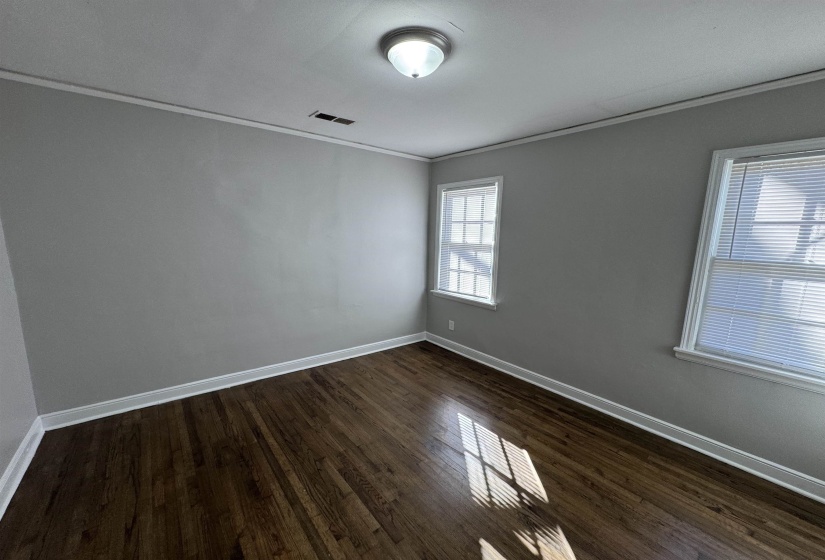 Empty room featuring ornamental molding and dark wood-type flooring