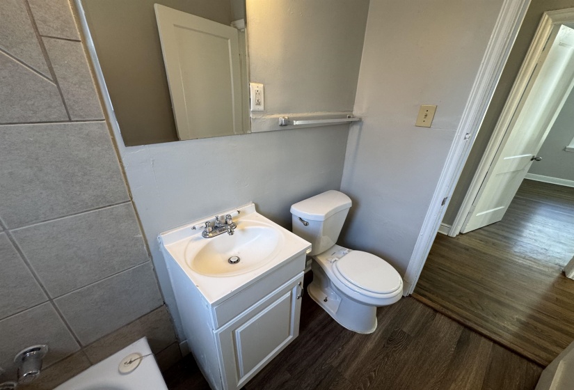 Full bathroom featuring vanity, dark wood-style flooring, and a tub to relax in