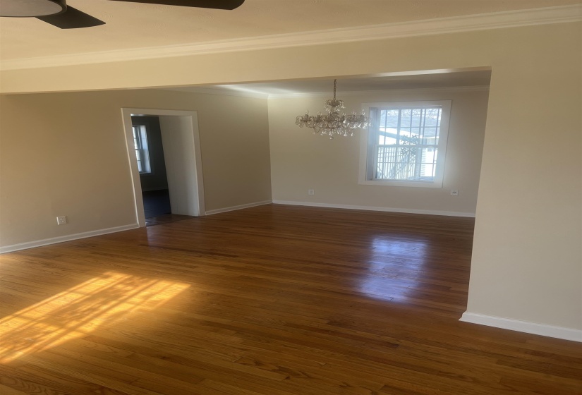 Spare room featuring crown molding, a ceiling fan, dark wood finished floors, and a chandelier