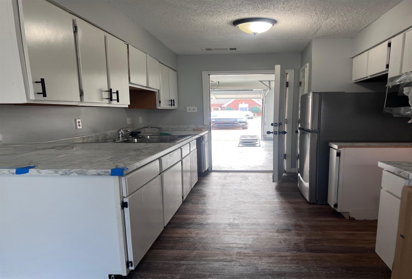 Kitchen featuring dark wood finished floors, freestanding refrigerator, light countertops, a textured ceiling, and white cabinets