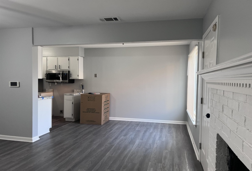 Kitchen with white cabinets, dark wood-style floors, light countertops, and stainless steel microwave