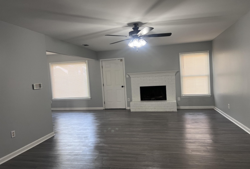 Unfurnished living room with dark wood finished floors, a fireplace, and plenty of natural light