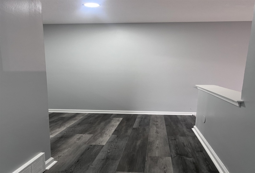 Empty room featuring dark wood-type flooring and recessed lighting