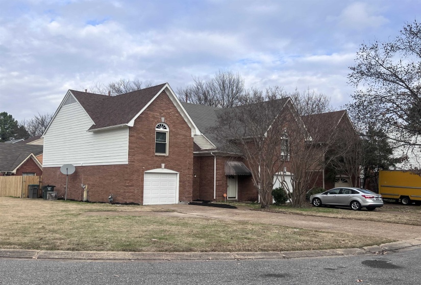 Traditional-style house with brick siding, a garage, a shingled roof, a front yard, and driveway