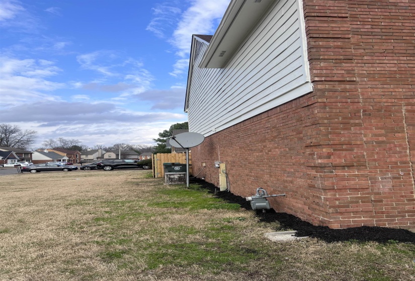 View of side of home with a residential view, brick siding, and a yard