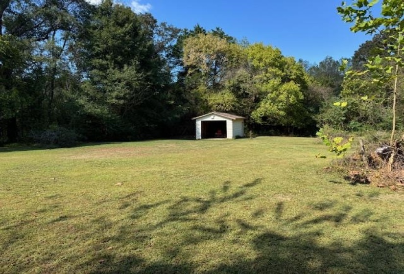 View of green lawn featuring an outbuilding