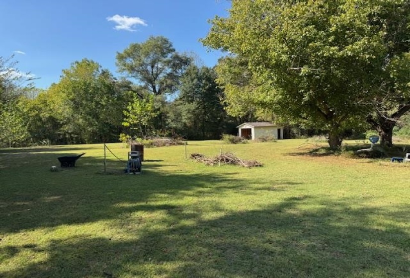 View of property's community with a yard, an outdoor structure, and view of wooded area