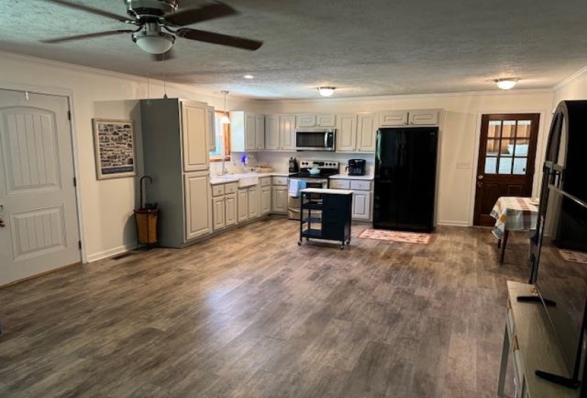Kitchen featuring a textured ceiling, stainless steel appliances, light countertops, crown molding, and a ceiling fan