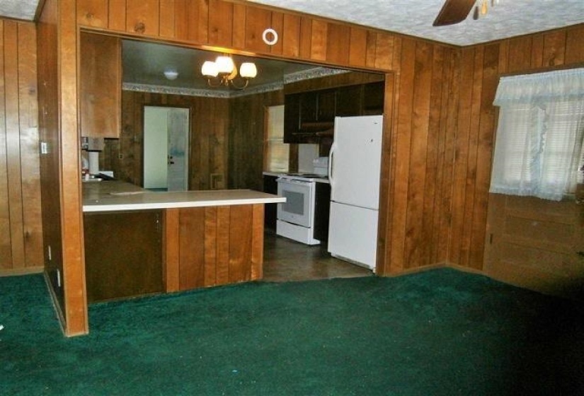 Kitchen featuring white appliances, wooden walls, and brown cabinetry