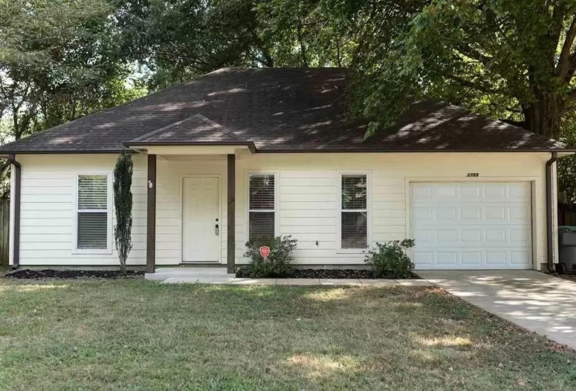 Ranch-style house featuring a garage, a front yard, driveway, and roof with shingles
