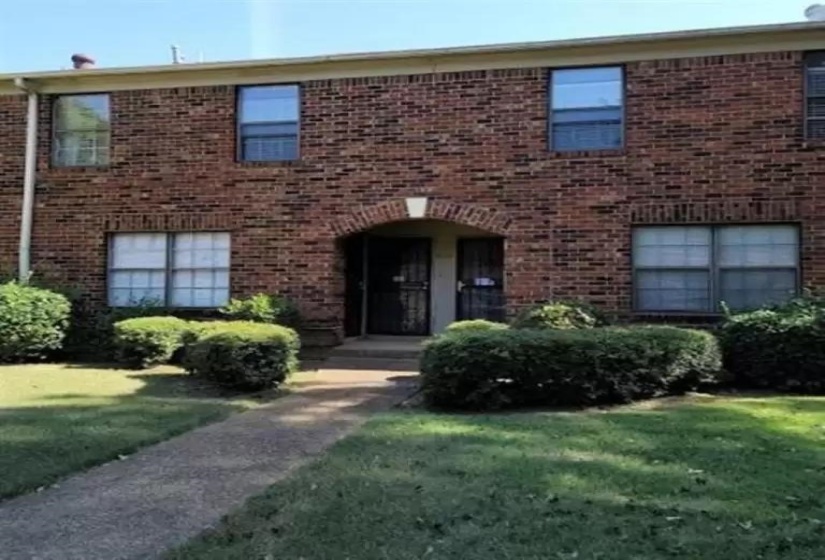 View of property featuring brick siding and a front yard