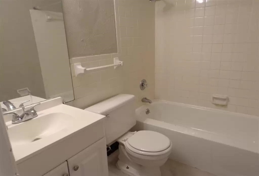 Full bathroom with toilet, shower / washtub combination, vanity, and tile walls
