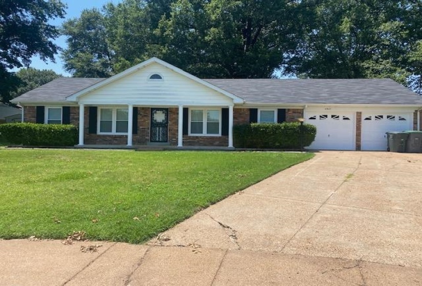 Ranch-style home with a garage, a front yard, driveway, brick siding, and a porch