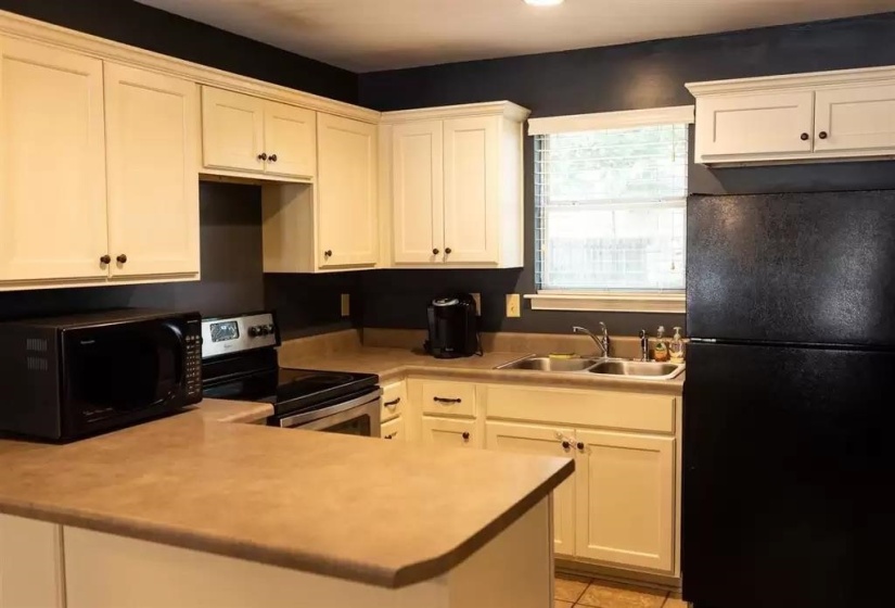 Kitchen with black appliances, a sink, white cabinets, and a peninsula