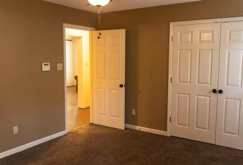 Unfurnished bedroom with dark carpet, a closet, and baseboards