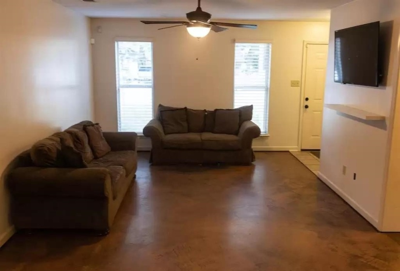 Living area with a ceiling fan, healthy amount of natural light, and baseboards