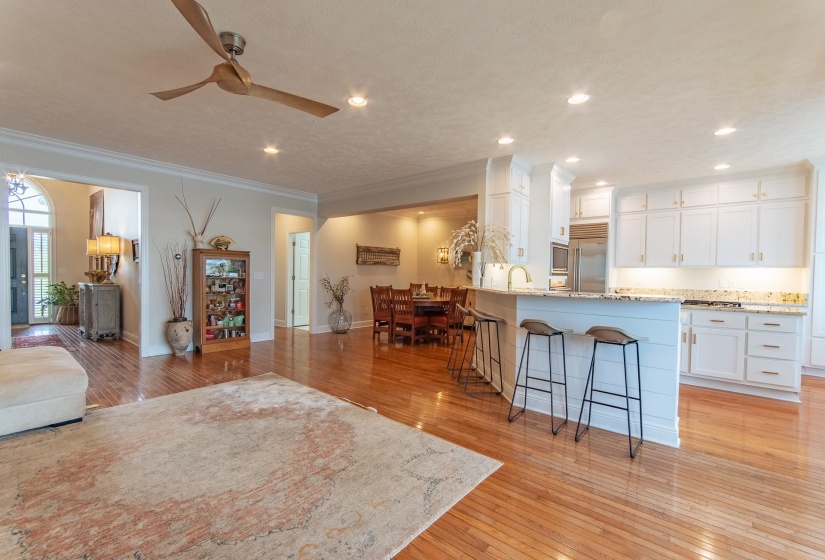 Living room featuring a ceiling fan, baseboards, ornamental molding, recessed lighting, and light wood-style flooring