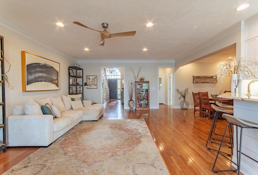 Living room with crown molding, hardwood / wood-style floors, baseboards, ceiling fan, and recessed lighting