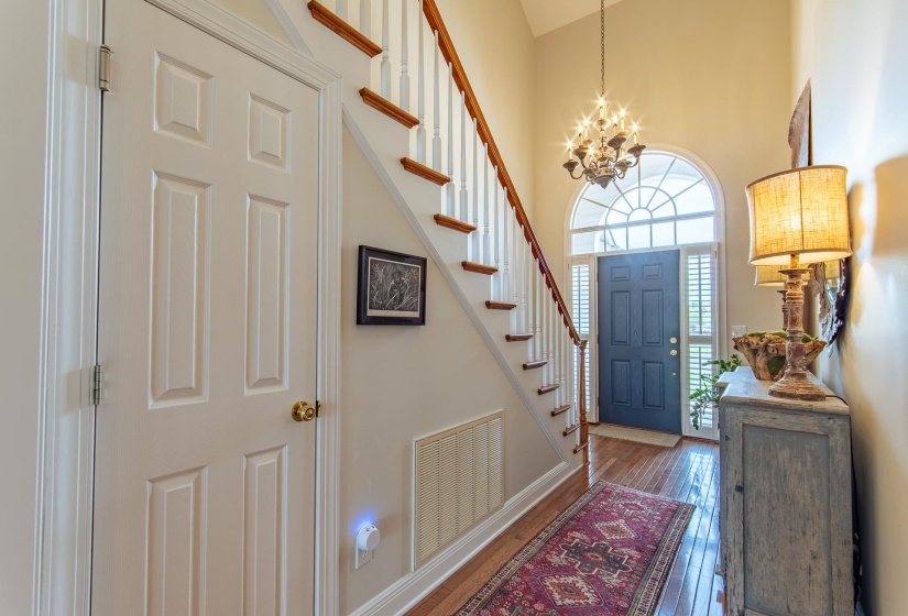 Entrance foyer with visible vents, an inviting chandelier, stairs, a high ceiling, and hardwood / wood-style flooring