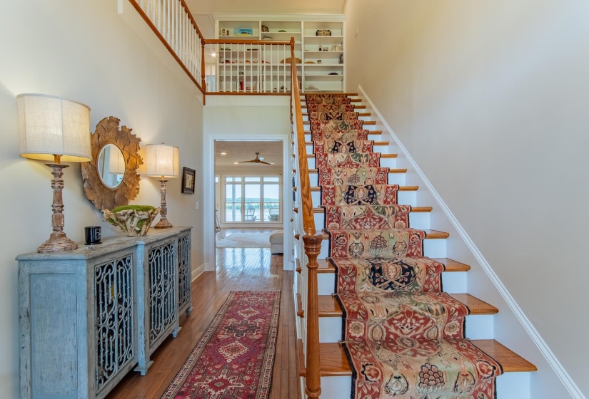 Staircase featuring baseboards, wood finished floors, and a towering ceiling