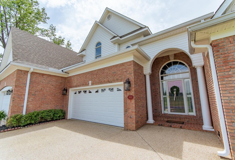 Exterior space featuring concrete driveway, brick siding, and roof with shingles