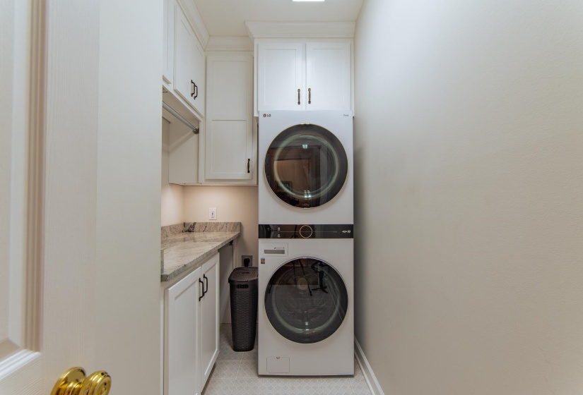 Laundry area featuring baseboards, stacked washer / drying machine, and cabinet space