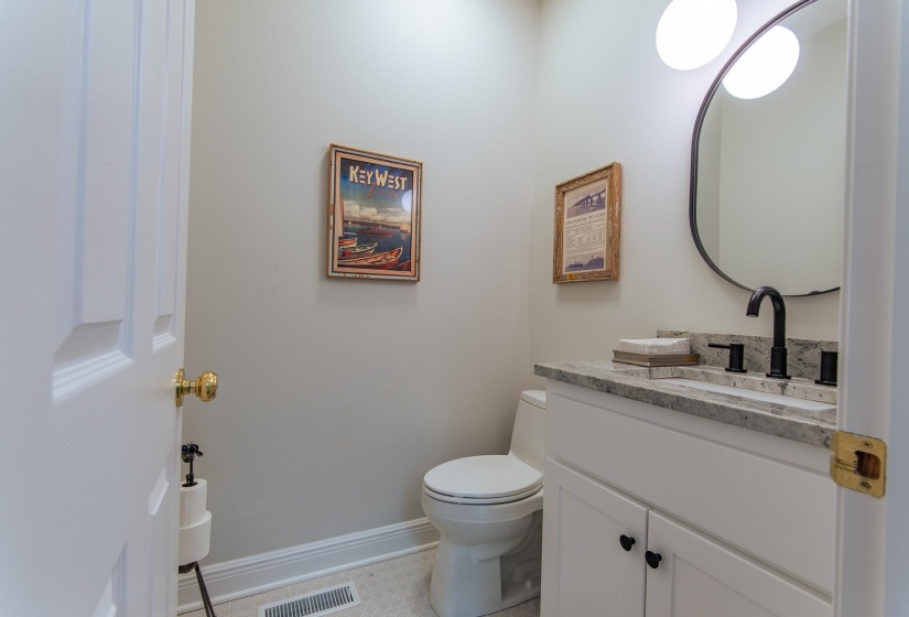 Half bathroom featuring vanity, toilet, tile patterned floors, baseboards, and visible vents