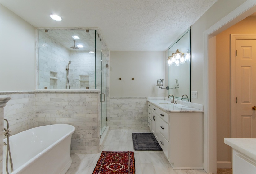Bathroom with tile walls, a shower stall, vanity, a wainscoted wall, and a soaking tub