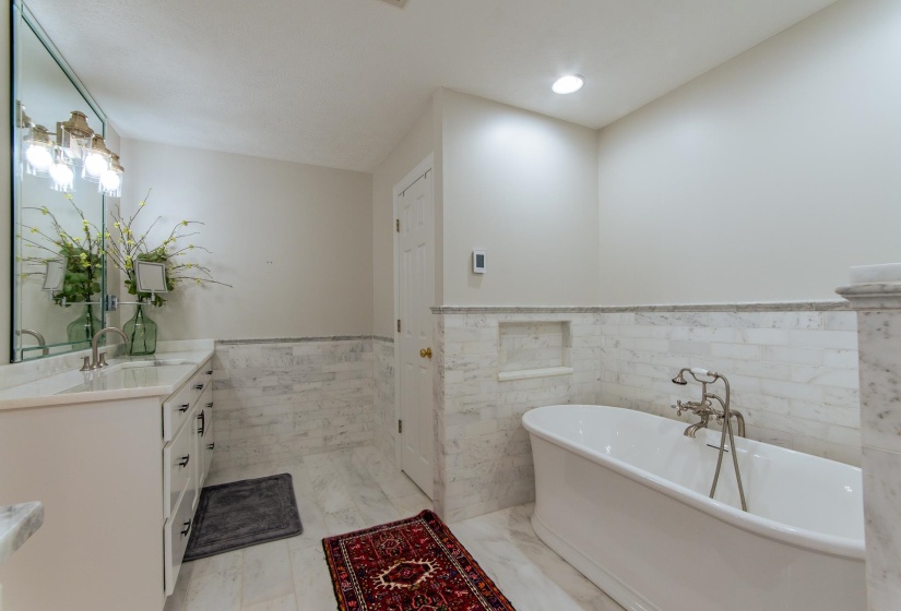 Full bathroom featuring vanity, a freestanding tub, tile walls, recessed lighting, and a wainscoted wall