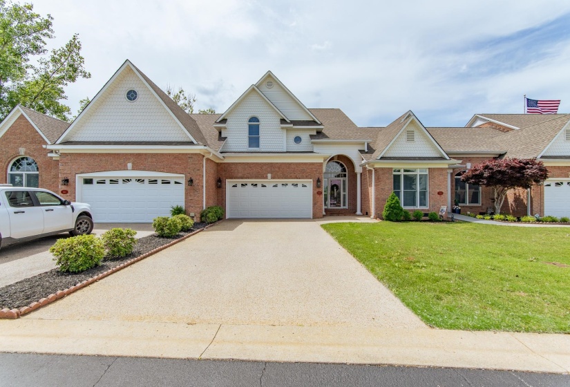 View of front facade featuring concrete driveway, brick siding, a shingled roof, and a front yard