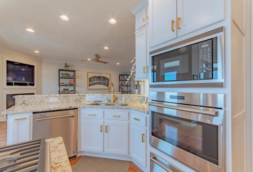 Kitchen with crown molding, a sink, light stone counters, a peninsula, and stainless steel appliances