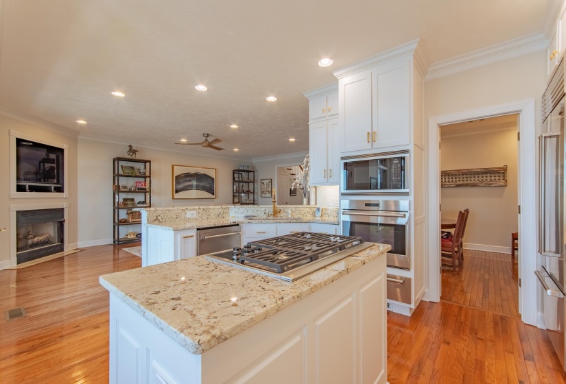 Kitchen featuring a kitchen island, a peninsula, appliances with stainless steel finishes, and ornamental molding