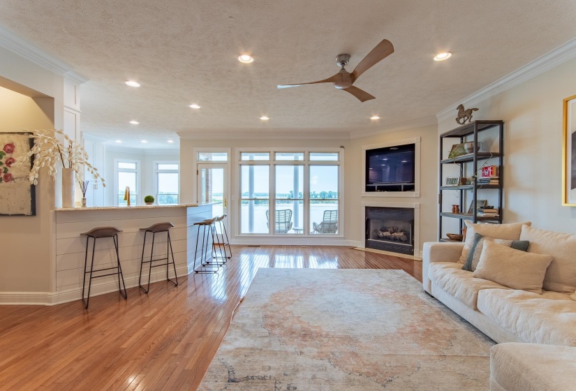 Living area with a ceiling fan, crown molding, a fireplace, light wood-type flooring, and recessed lighting