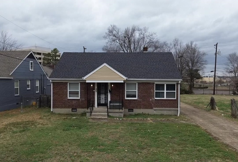 View of front of home with brick siding, a front lawn, and crawl space
