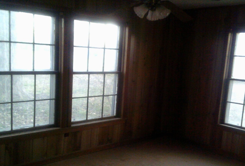 Empty room with ceiling fan, plenty of natural light, and wooden walls