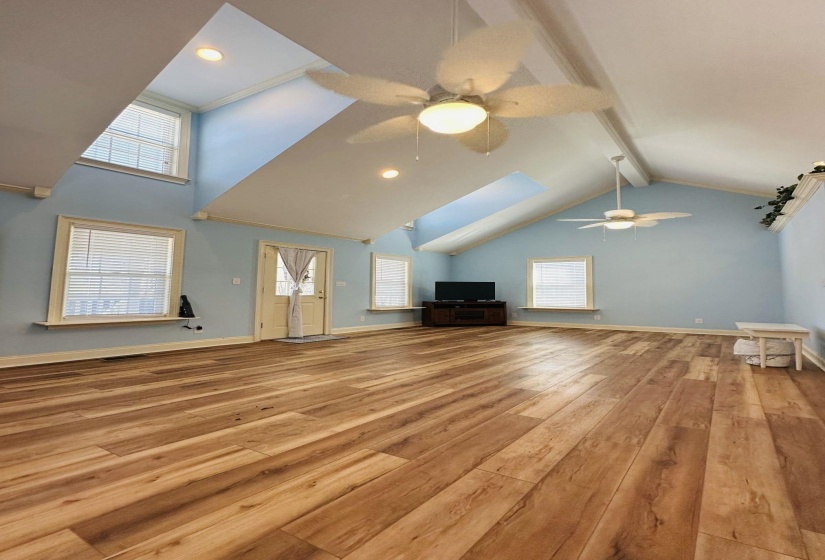 Living room with wood laminate hardwood flooring and vaulted ceiling.