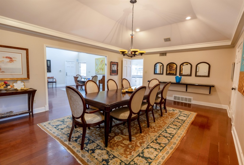 Dining area with ornamental molding, dark wood-type flooring, and a chandelier