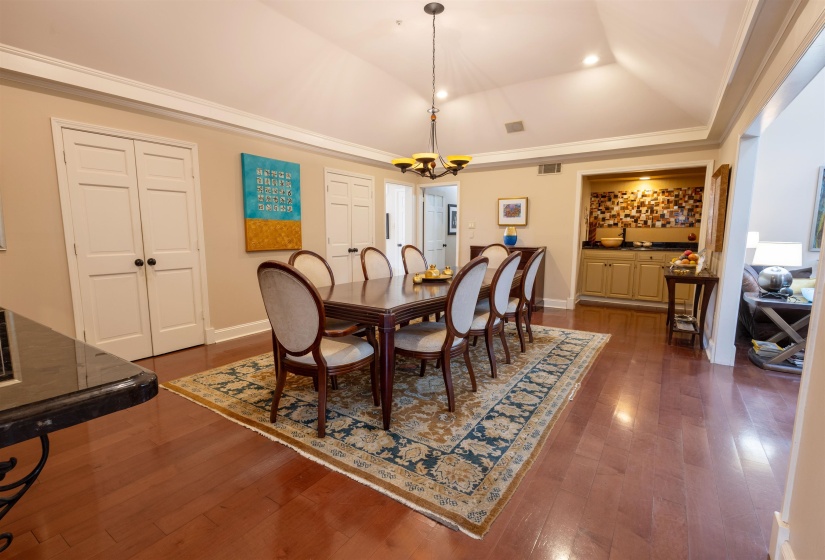 Dining space with a chandelier, dark wood-style flooring, and crown molding