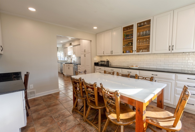 Kitchen featuring white cabinetry, decorative backsplash, glass insert cabinets, dark stone countertops, and stainless steel dishwasher