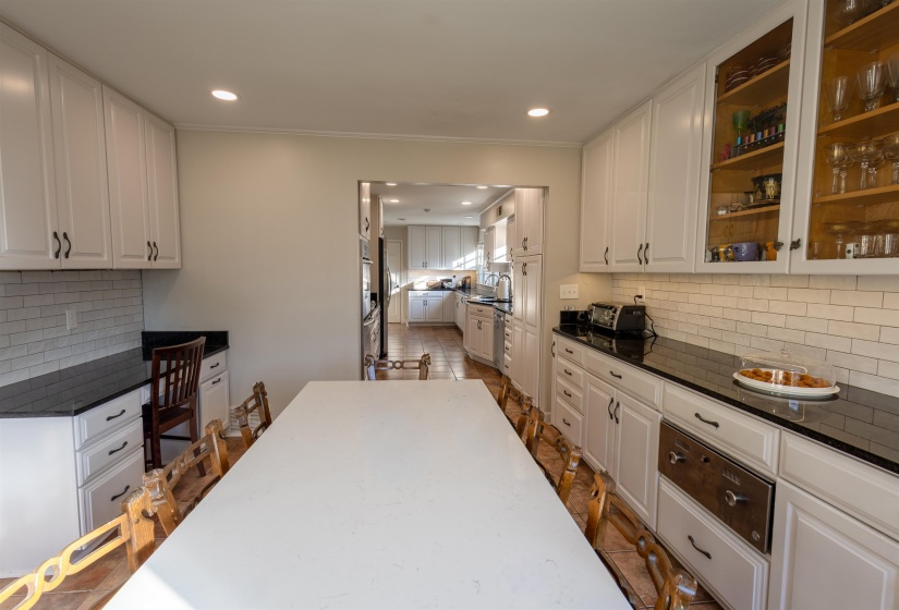 Kitchen with backsplash, white cabinets, glass insert cabinets, dark stone countertops, and recessed lighting