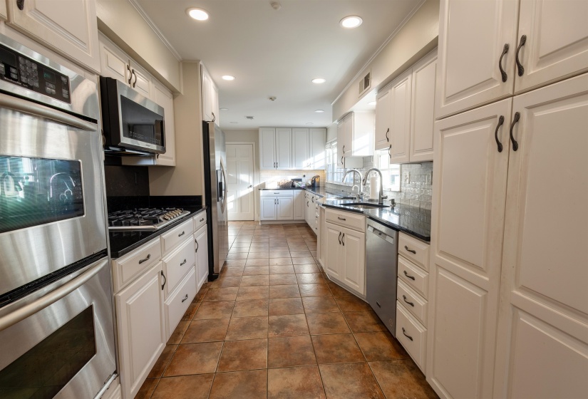 Kitchen with appliances with stainless steel finishes, white cabinets, recessed lighting, dark stone counters, and decorative backsplash
