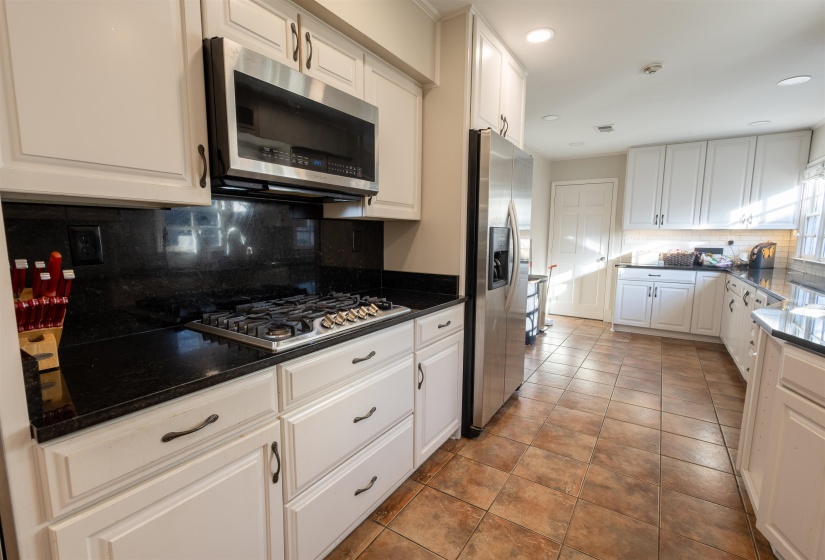 Kitchen with white cabinets, stainless steel appliances, tasteful backsplash, light tile patterned floors, and recessed lighting