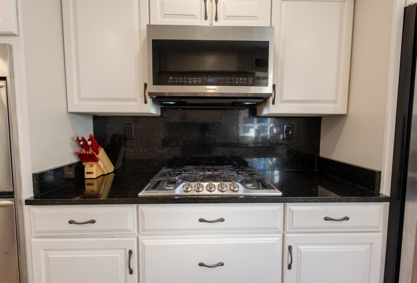 Kitchen featuring appliances with stainless steel finishes, white cabinets, dark stone counters, and backsplash